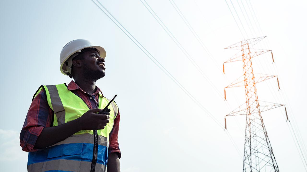 An electrical engineer looks up at a utility tower