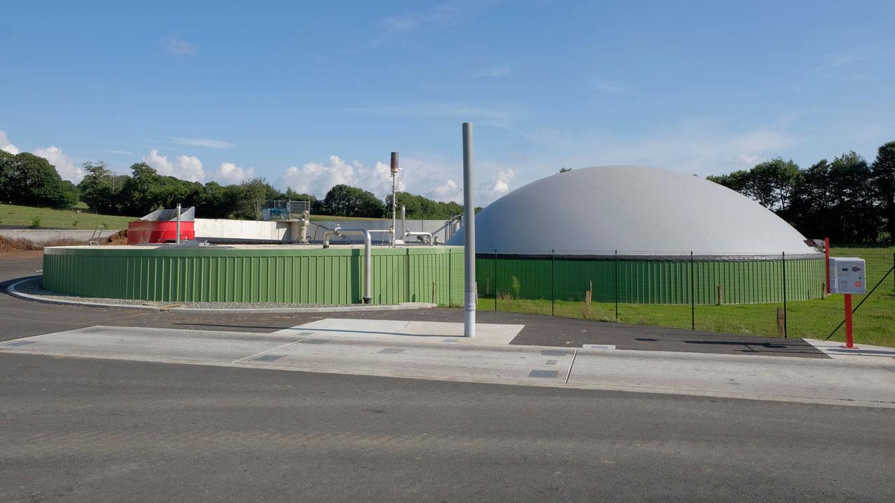 Anaerobic digestion facility for conversion of organic waste with fencing around it and a blue sky in the background