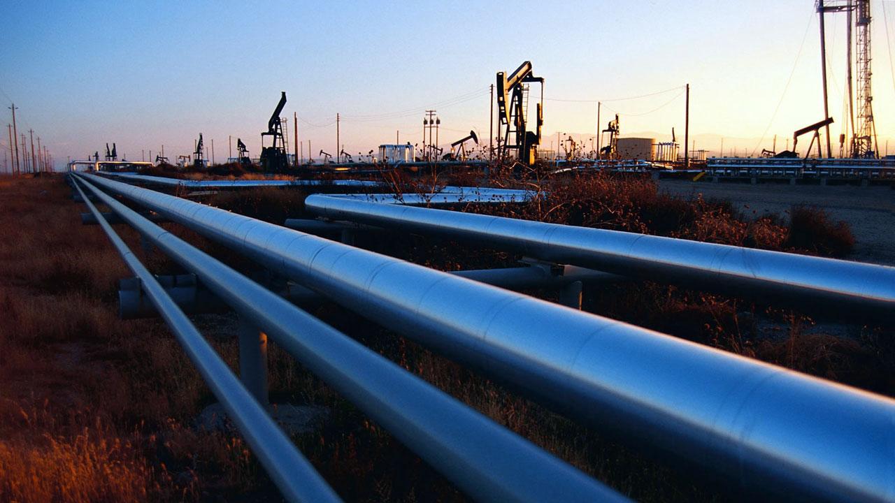 Blue metallic pipelines running through oil field at sunset