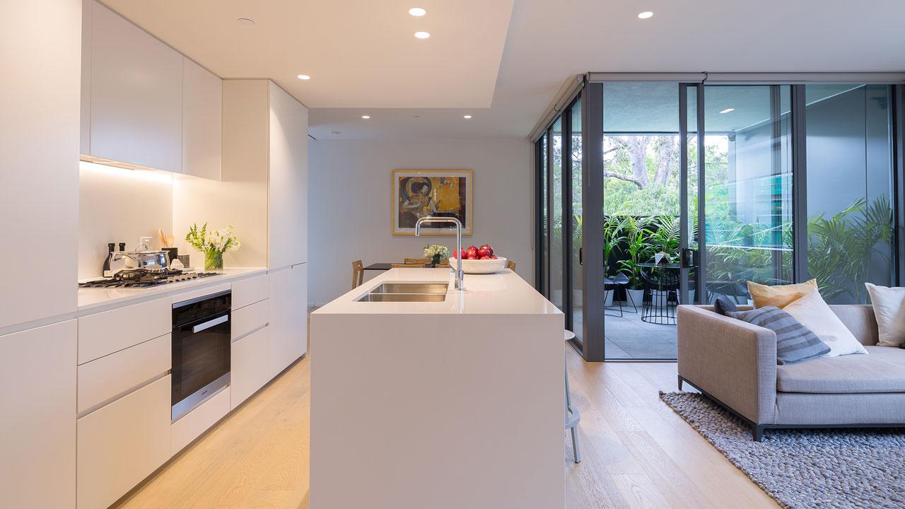 A kitchen area in a residential apartment with a terrace area beyond a sliding glass door
