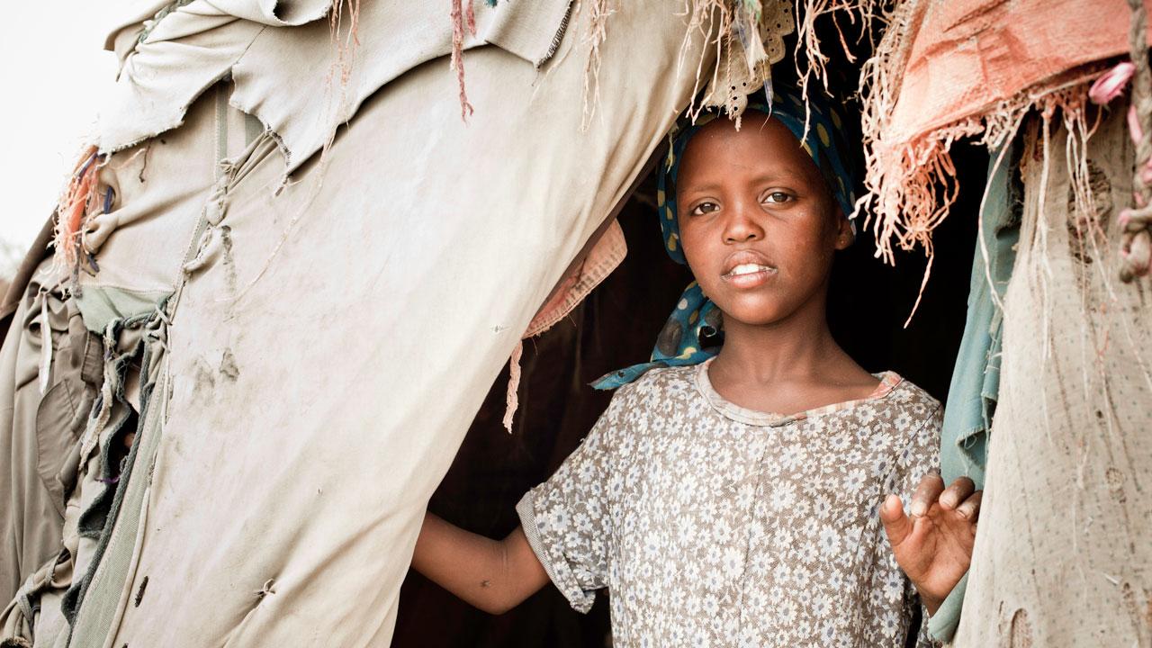 在一个国内流离失所者营地，一个年轻的索马里女孩从她的小屋向外望去